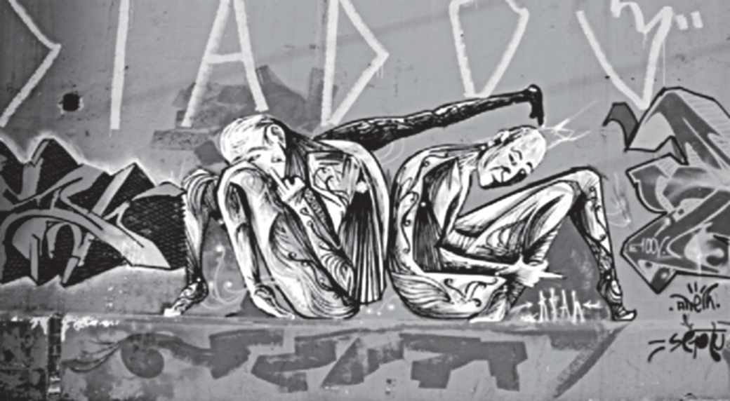 Fotografia em preto e branco de um grafite em muro urbano: duas figuras humanas magras, agachadas e contorcidas, desenhadas com traços brancos e cinzas, uma delas com o braço estendido sobre a outra; ao fundo, letras grandes e estilizadas e assinaturas de grafiteiros.