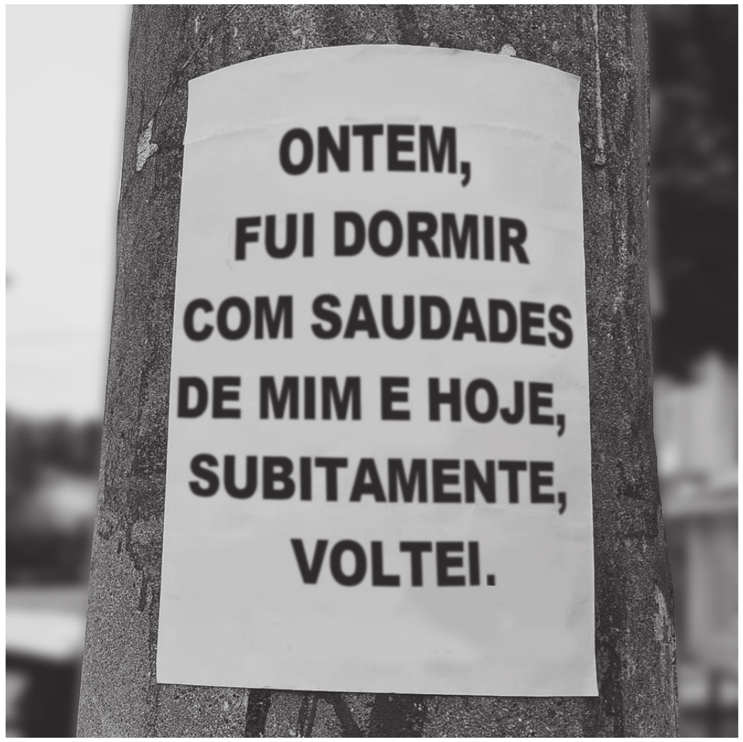 Fotografia de um cartaz de papel colado num poste de concreto, na rua, com o fundo desfocado. O cartaz traz, em letras pretas maiúsculas, um poema em seis linhas.

ONTEM,
FUI DORMIR
COM SAUDADES
DE MIM E HOJE,
SUBITAMENTE,
VOLTEI.