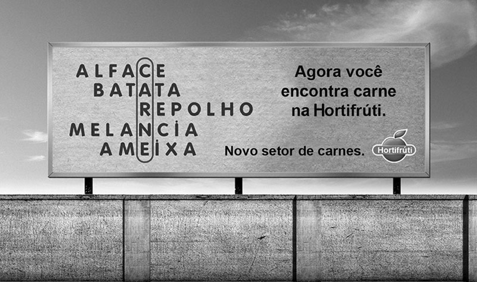 Outdoor sobre um muro. À esquerda, um caça-palavras com as palavras ALFACE, BATATA, REPOLHO, MELANCIA e AMEIXA; uma letra de cada uma, circulada na vertical, forma a palavra CARNE. À direita, o texto "Agora você encontra carne na Hortifrúti. Novo setor de carnes." e o logotipo da Hortifrúti.