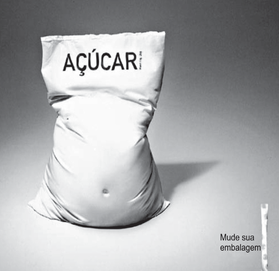 Fotografia publicitária em preto e branco: um saco de açúcar com o rótulo "AÇÚCAR" moldado como um tronco humano gordo, com barriga saliente e umbigo, em pé sobre uma superfície clara; à direita, bem menor, um sachê fino de adoçante, ao lado do texto "Mude sua embalagem".