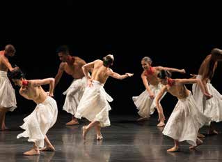 Fotografia de sete bailarinos em cena, vestidos de branco, durante o espetáculo Gira.