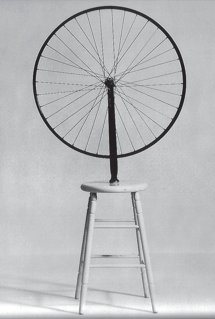 Fotografia em preto e branco da obra: uma roda de bicicleta com raios, montada de cabeça para baixo pelo garfo sobre o assento de um banquinho de madeira de quatro pernas, contra um fundo claro e liso.