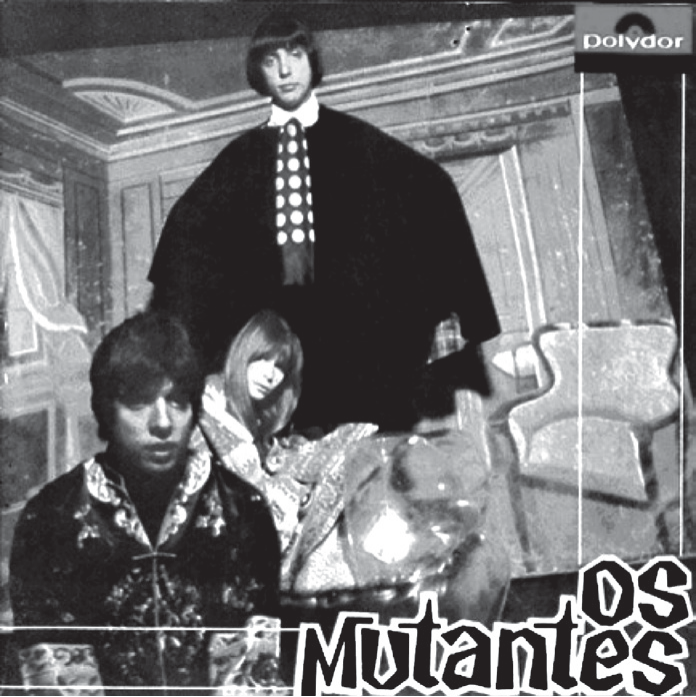 Capa do LP Os Mutantes (Polydor, 1968), fotografia em preto e branco: os três integrantes em um salão antigo, um em pé, de capa preta e camisa de bolinhas, e dois sentados à frente, com roupas extravagantes; no canto inferior direito, o nome "Os Mutantes" em letras grandes.