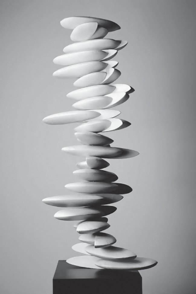 Fotografia em preto e branco de uma escultura de Norma Grimberg: dezenas de discos ovais de cerâmica clara, de tamanhos e inclinações variados, empilhados de forma irregular formando duas colunas entrelaçadas que sobem em torção sobre um pedestal preto.