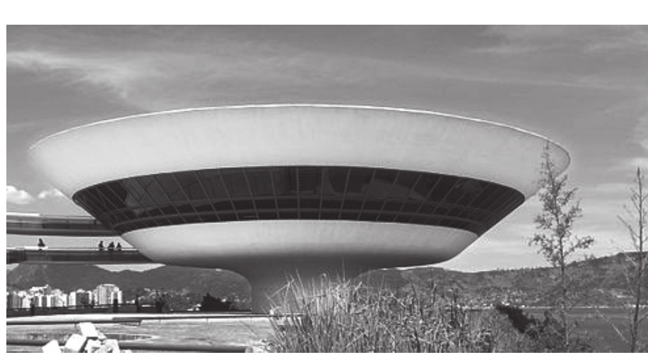 Fotografia em preto e branco do Museu de Arte Contemporânea de Niterói: um edifício em forma de disco ou taça invertida, com faixa de janelas escuras ao redor, apoiado sobre uma base estreita, com o céu ao fundo, uma rampa curva à esquerda e vegetação em primeiro plano.