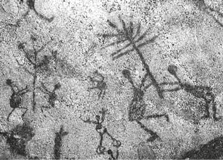 Fotografia de pintura rupestre em rocha clara: várias figuras humanas estilizadas, em tom escuro, com braços erguidos e pernas abertas como se dançassem ou corressem; no alto, uma figura maior com forma de árvore ou raios; à direita, duas figuras parecem lutar ou dançar em par.